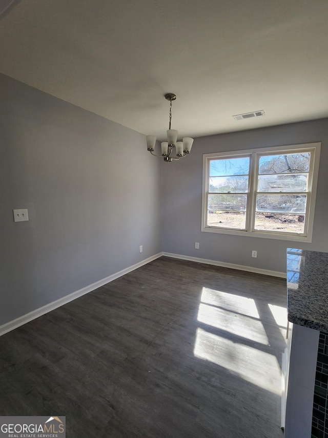 unfurnished dining area with an inviting chandelier and dark hardwood / wood-style flooring