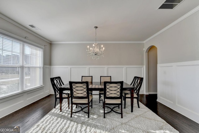 dining room with dark wood-type flooring, ornamental molding, and a chandelier