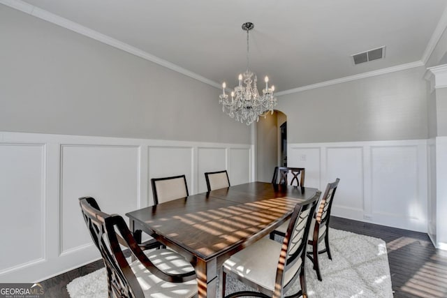 dining area featuring crown molding, dark hardwood / wood-style floors, and an inviting chandelier