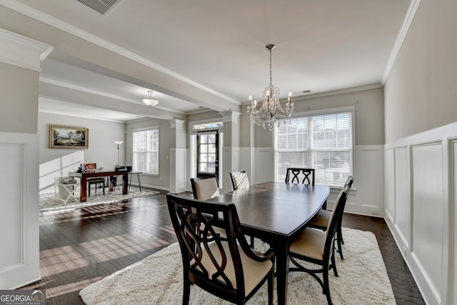 dining space featuring decorative columns, crown molding, dark hardwood / wood-style floors, and a chandelier