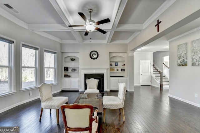 living room with coffered ceiling, dark wood-type flooring, beam ceiling, and built in shelves