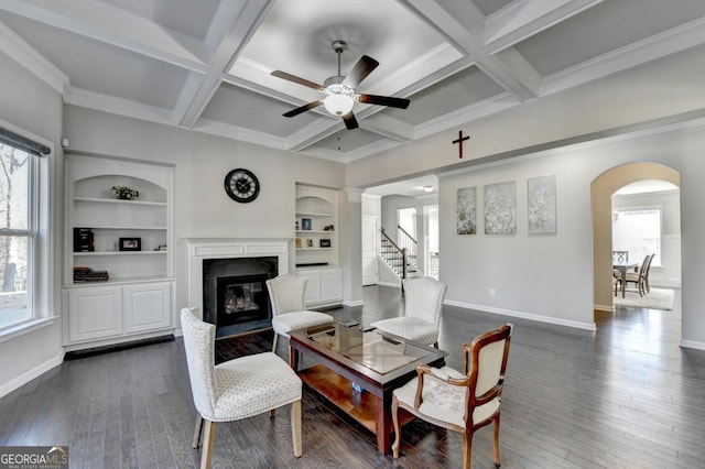 living room featuring dark hardwood / wood-style flooring, built in shelves, coffered ceiling, and beamed ceiling