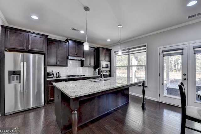 kitchen featuring sink, light stone counters, a center island with sink, appliances with stainless steel finishes, and pendant lighting