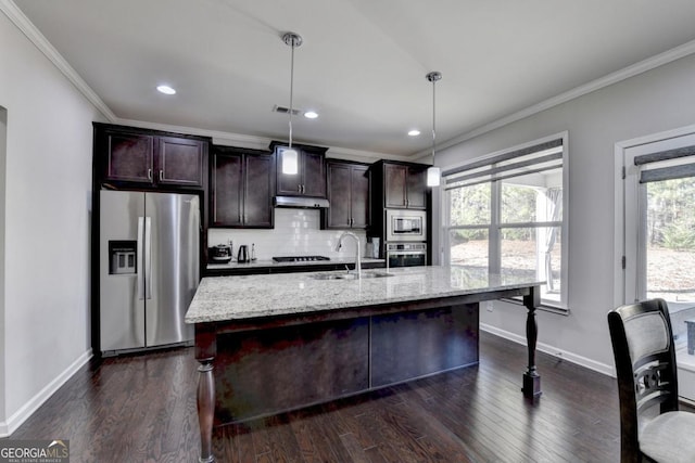 kitchen featuring appliances with stainless steel finishes, a kitchen island with sink, sink, and hanging light fixtures