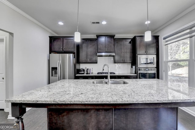 kitchen featuring stainless steel appliances, dark brown cabinets, pendant lighting, and light stone counters