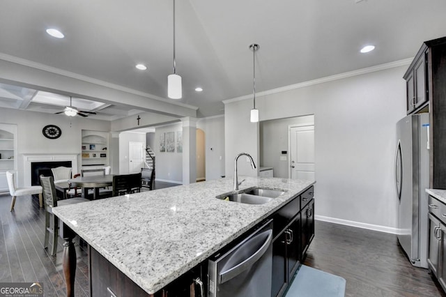 kitchen with dark wood-type flooring, appliances with stainless steel finishes, sink, and a center island with sink