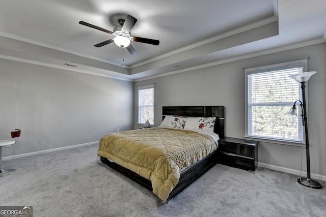 carpeted bedroom with ceiling fan, ornamental molding, and a raised ceiling