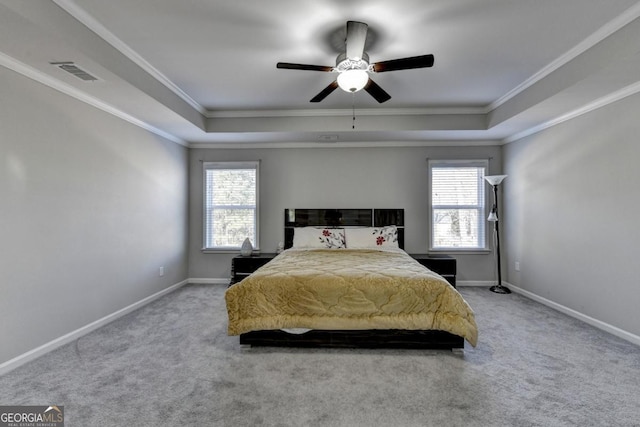 carpeted bedroom with ornamental molding, ceiling fan, and a tray ceiling