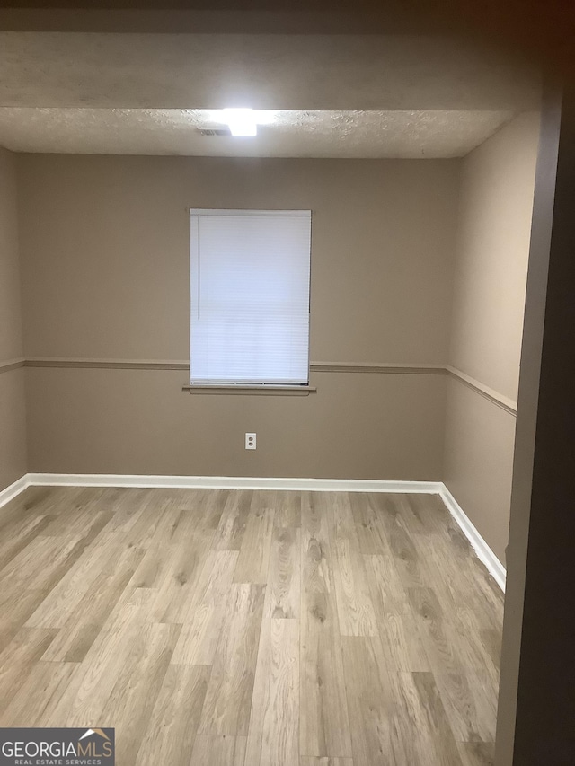 unfurnished room featuring light hardwood / wood-style flooring and a textured ceiling