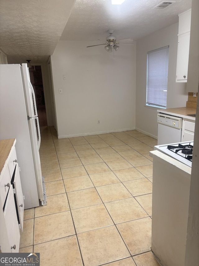 kitchen featuring white appliances, white cabinets, and light tile patterned flooring