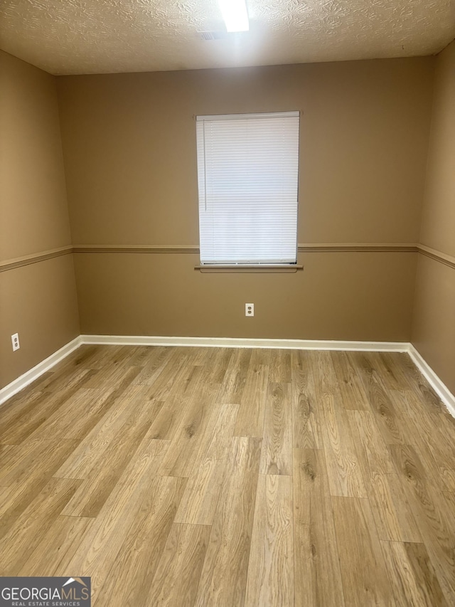 empty room with a textured ceiling and light wood-type flooring