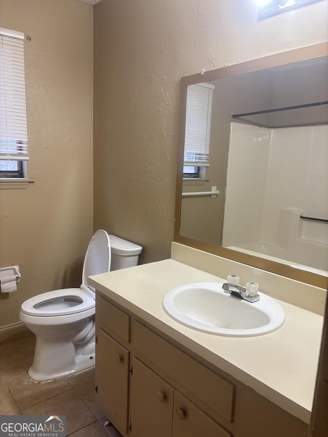 bathroom with tile patterned flooring, vanity, a shower, and toilet