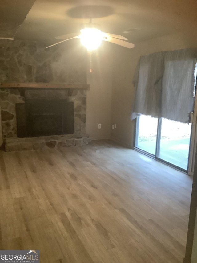 unfurnished living room featuring wood-type flooring, ceiling fan, and a fireplace