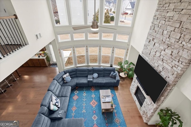 living room with a healthy amount of sunlight, a towering ceiling, hardwood / wood-style floors, and a fireplace