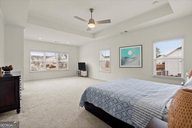 bedroom with a raised ceiling, light colored carpet, and ceiling fan