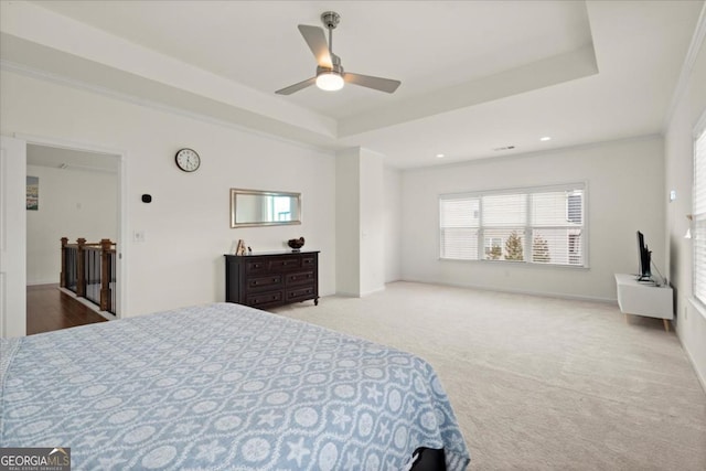 carpeted bedroom with a raised ceiling and ceiling fan