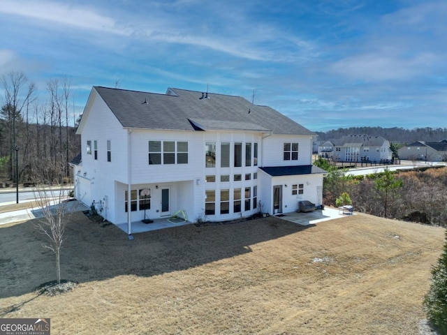 back of property with a yard and a patio