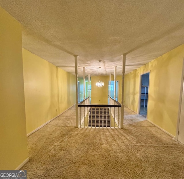 basement with carpet flooring, a chandelier, and a textured ceiling