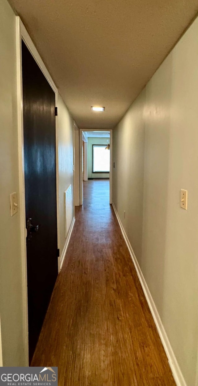 hall featuring dark wood-type flooring and a textured ceiling