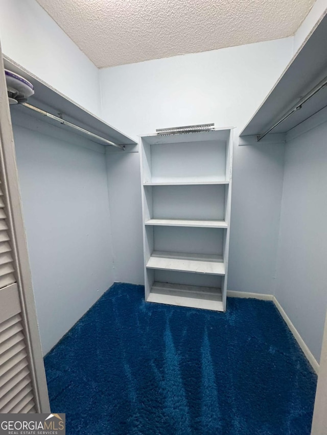 walk in closet featuring dark carpet