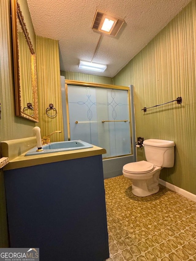 full bathroom featuring vanity, combined bath / shower with glass door, toilet, and a textured ceiling