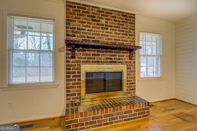 details featuring ornamental molding, wood-type flooring, a brick fireplace, and wood walls