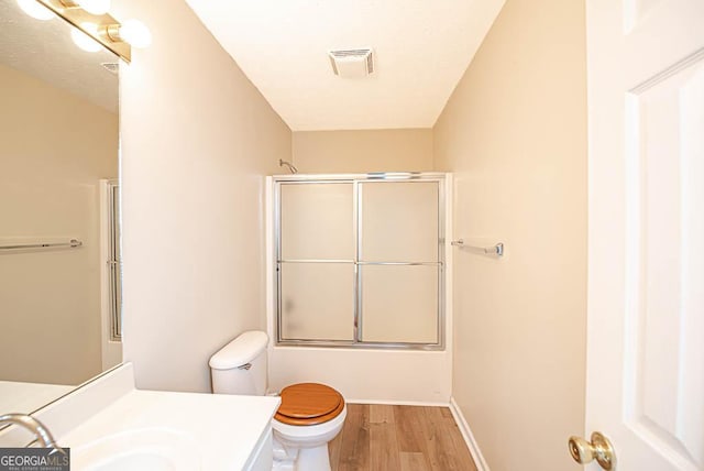 full bathroom featuring toilet, vanity, shower / bath combination with glass door, and hardwood / wood-style floors