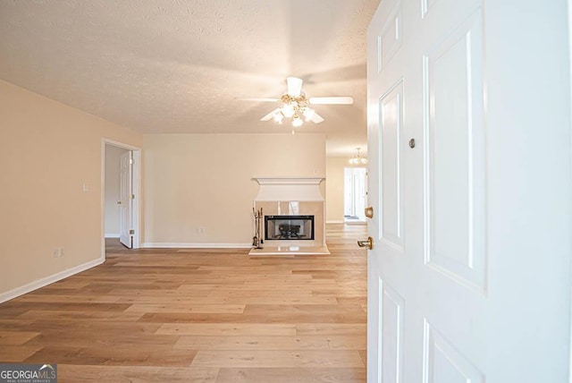 unfurnished living room with ceiling fan, a textured ceiling, and light wood-type flooring