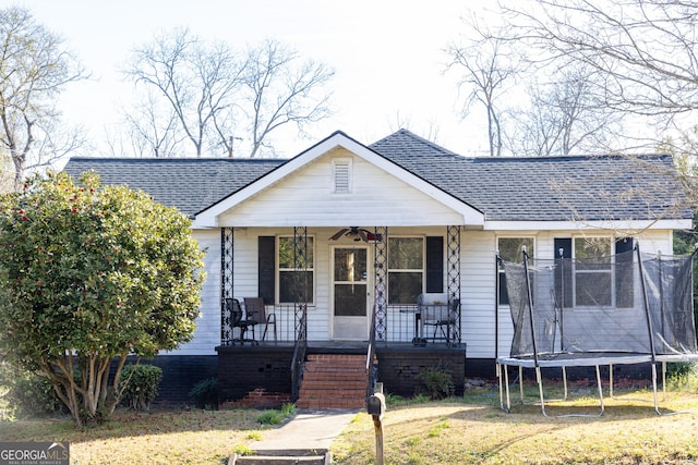 bungalow with a trampoline, covered porch, roof with shingles, and a ceiling fan