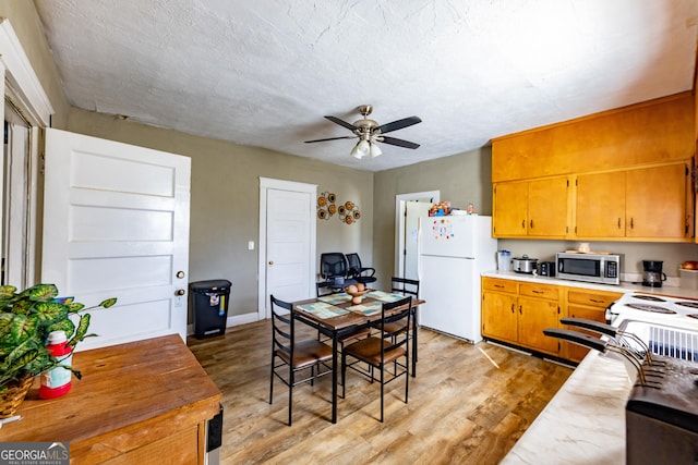 kitchen featuring light countertops, light wood finished floors, stainless steel microwave, and freestanding refrigerator