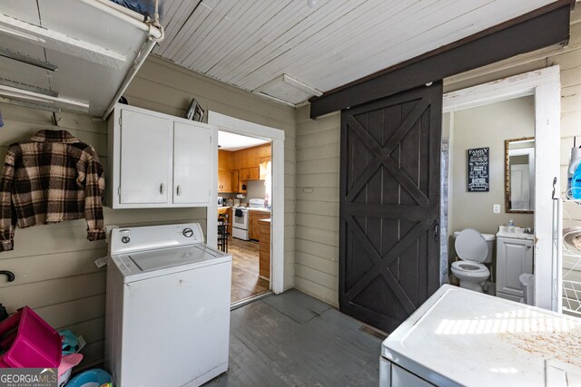 laundry room with cabinet space, wooden walls, washer / clothes dryer, and dark wood finished floors