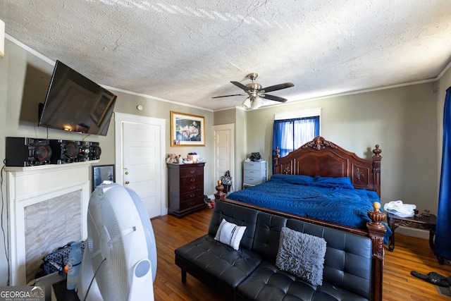 bedroom with crown molding, a textured ceiling, ceiling fan, and wood finished floors