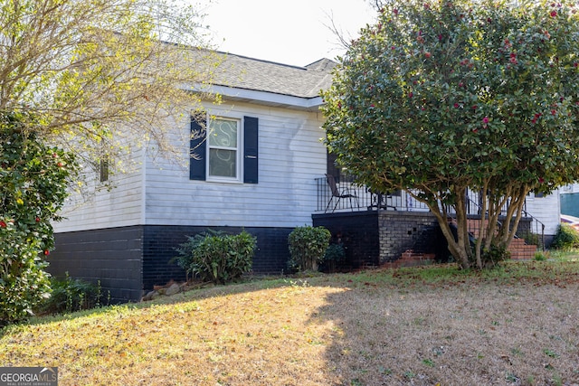 view of property exterior featuring a shingled roof and a lawn