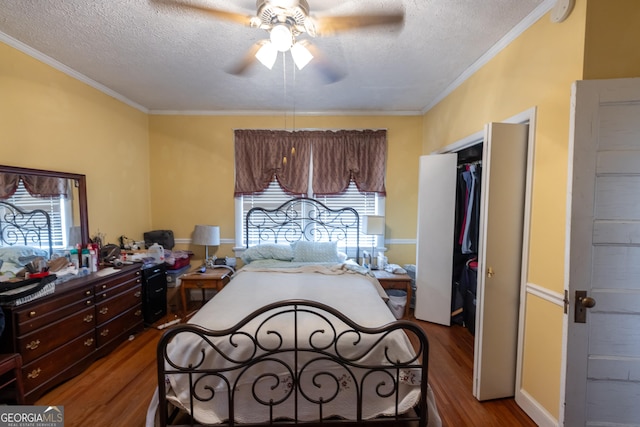 bedroom with a closet, wood-type flooring, a textured ceiling, ceiling fan, and ornamental molding