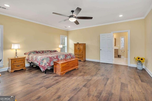 bedroom with dark wood-style floors, crown molding, visible vents, ensuite bath, and baseboards