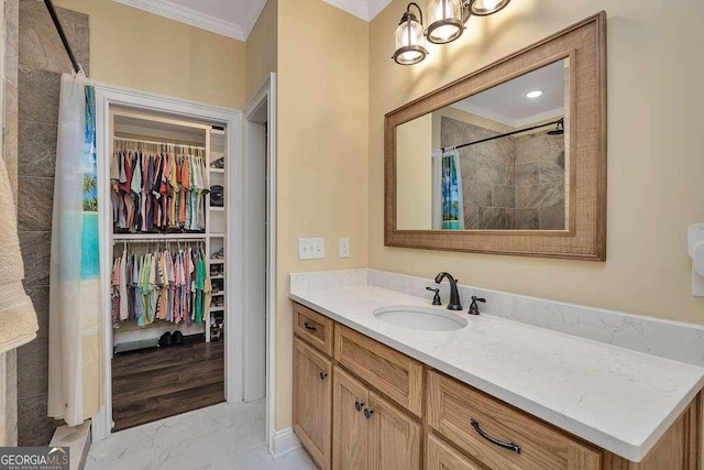 bathroom with ornamental molding, tiled shower, a spacious closet, and vanity