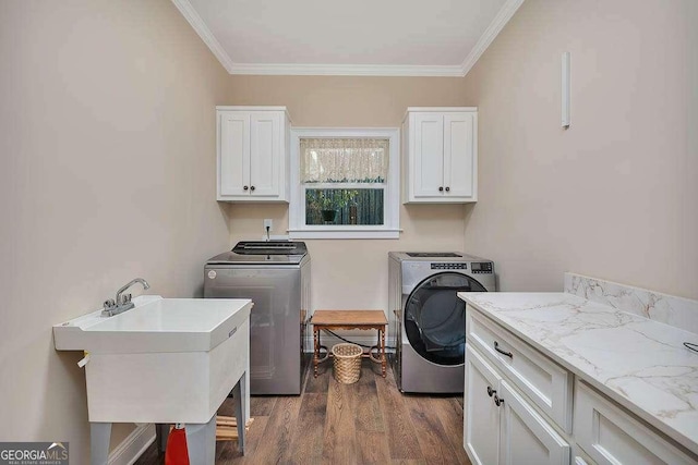 washroom with washing machine and dryer, a sink, cabinet space, dark wood finished floors, and crown molding