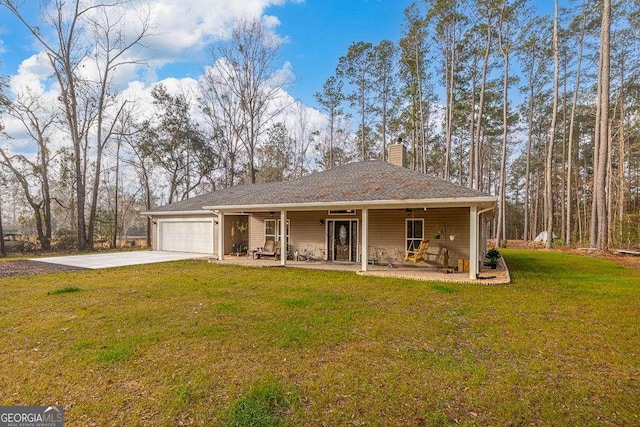 view of front of house with a chimney, concrete driveway, covered porch, an attached garage, and a front yard