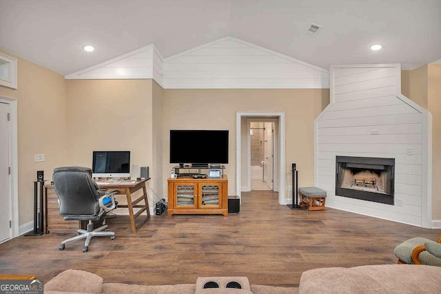 interior space featuring a fireplace, vaulted ceiling, and wood finished floors