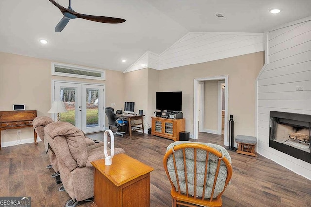 living area with a fireplace, wood finished floors, a ceiling fan, vaulted ceiling, and french doors