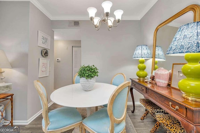 dining space with hardwood / wood-style flooring, ornamental molding, and a chandelier