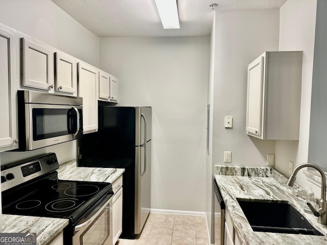 1704 Frederica Rd Unit 325, Saint Simons, GA 31522 - kitchen featuring appliances with stainless steel finishes, light stone counters, light tile patterned floors, and white cabinetry
