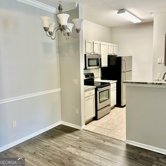 1704 Frederica Rd Unit 325, Saint Simons, GA 31522 - kitchen featuring stainless steel appliances, white cabinetry, light wood-style flooring, a chandelier, and ornamental molding