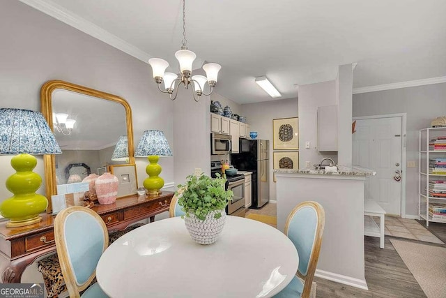 dining area with ornamental molding, a chandelier, and light hardwood / wood-style flooring