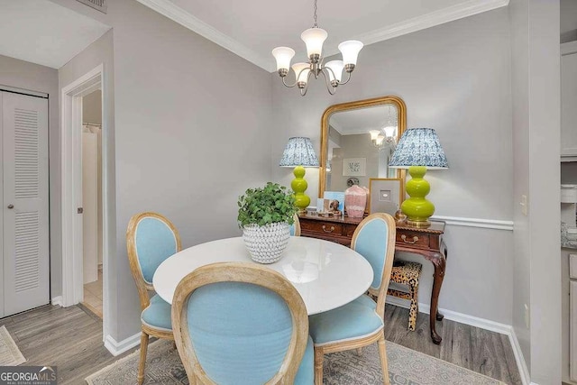 dining space with crown molding, a notable chandelier, and light hardwood / wood-style floors