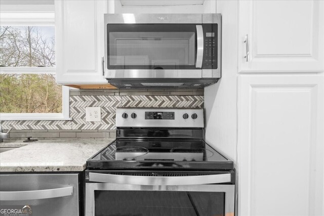 kitchen with white cabinetry, decorative backsplash, light stone countertops, and appliances with stainless steel finishes