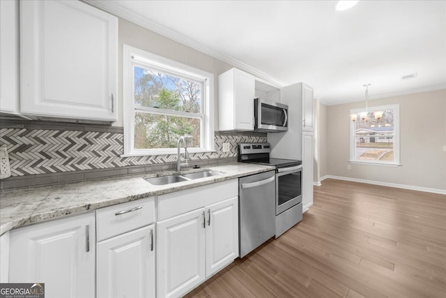 kitchen with sink, crown molding, decorative light fixtures, appliances with stainless steel finishes, and white cabinets