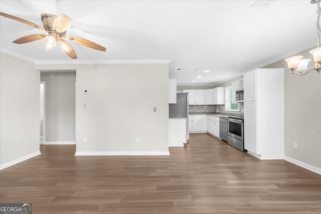 kitchen featuring appliances with stainless steel finishes, tasteful backsplash, white cabinets, dark hardwood / wood-style flooring, and crown molding