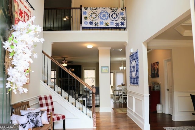 entrance foyer featuring a high ceiling, ornamental molding, ceiling fan, and dark hardwood / wood-style flooring