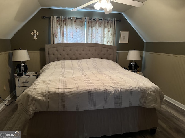 bedroom featuring multiple windows, wainscoting, wood finished floors, and lofted ceiling